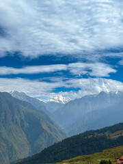 Naklejka premium Breathtaking View of Nanda Devi from Auli, India – Blue Skies and Green Meadows