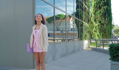 Young woman smiling, looking up while standing outdoors in the city