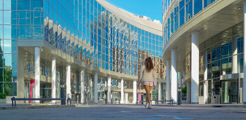 Woman walking confidently into a contemporary glass office complex, reflecting career aspirations