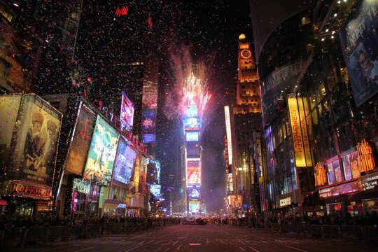 Times Square New York fireworks for New Year, crowd celebrating below, night skyline glowing, colorful bursts in sky, lively festive urban atmosphere, city celebration - Powered by Adobe