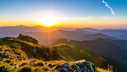Sun bursts over layered mountain peaks, green slopes in the foreground, and contrail in sky