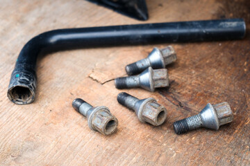 Lug wrench and wheel bolts on wooden surface