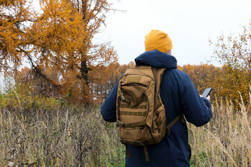 Hiker man navigating with phone in autumn nature