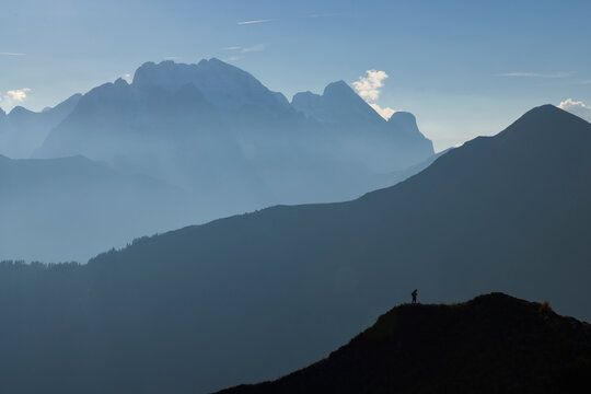 Hiker standing on ridge against distant Dolomite peak layering
