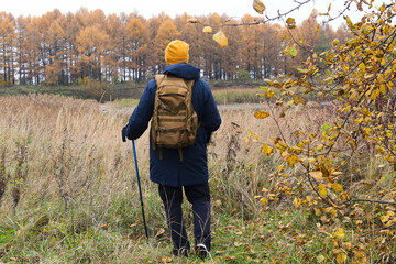 Man hiking through autumn landscape with walking pole
