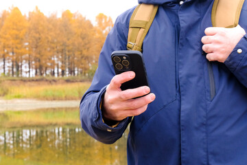 Traveler holding phone checking location on autumn hike