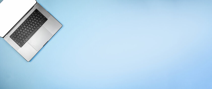 minimal tech desk, modern office setting featuring sleek silver laptop on blue surface, elegant workspace with minimalist design highlighting silver laptop in professional environment