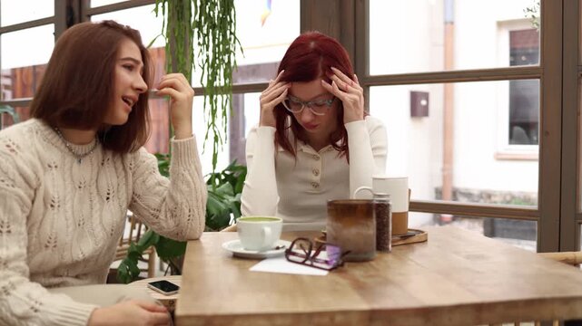 Two business partners sit together as one finally admits she is overwhelmed by multiple loans and financial pressure while the other listens quietly trying to understand and offer support