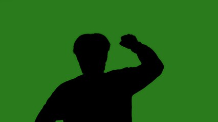 An isolated black silhouette of a man raising his hand in a protest against a green chroma key background. Minimalistic contrast and modern visual composition, mockup.