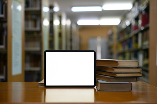 Stack of books with empty screen digital tablet in library
