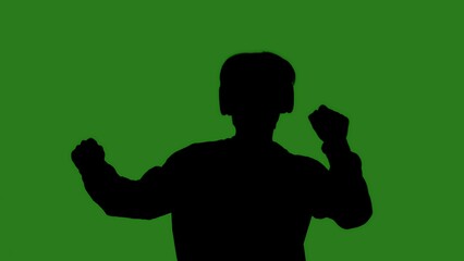 A black silhouette of a man wearing headphones dancing cheerfully against a green chroma key background. Minimalist contrast and modern visual composition, mockup.