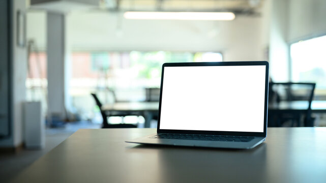 Laptop computer on meeting table with empty screen.