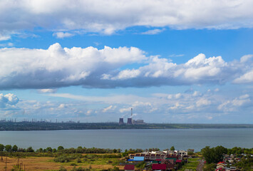 Power plant by lake under bright beautiful clouds