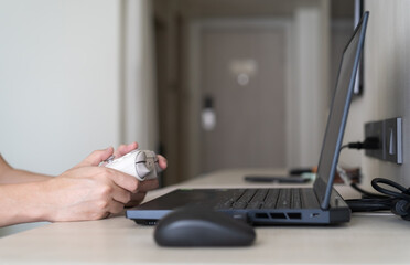 Closeup people hand or gamer holding joystick or wireless gaming controller to enjoy playing game on computer notebook or laptop console by joy stick in living room for entertrainment relax on holiday