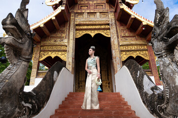 Beautiful young Asian woman in traditional Thai Dusit dress in an old temple in Chiang Mai, Thailand.