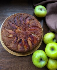 Homemade apple pie, a piece of apple pie and green apples on a dark wood background