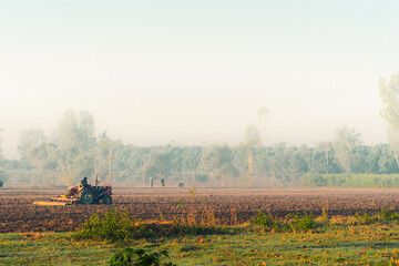 Fototapeta premium Agricultural tractor plowing field at sunrise rural farming scene for agriculture farming and harvest