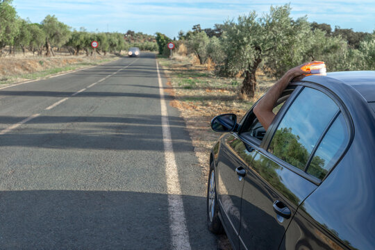 Driver signaling with V16 emergency warning beacon on car roof by roadside in Spain.	