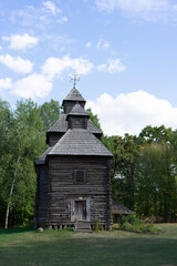 Wooden peasant church from the medieval period set among trees under a clear blue sky