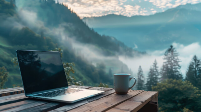 Laptop and coffee mug on table overlooking misty mountain landscape