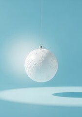 A minimalist white Christmas bauble with an embossed snowflake pattern. Vertical holiday decoration hanging against a solid light blue background with copy space
