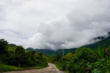 Remote mountain road winding through jungle hills under storm clouds, Vang Vieng, Laos