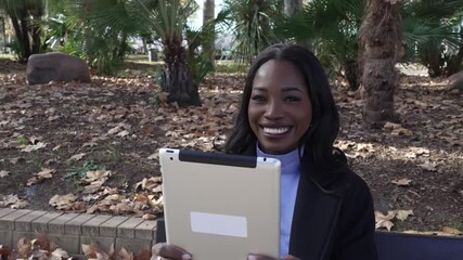 African american businesswoman video calling on tablet in autumn park