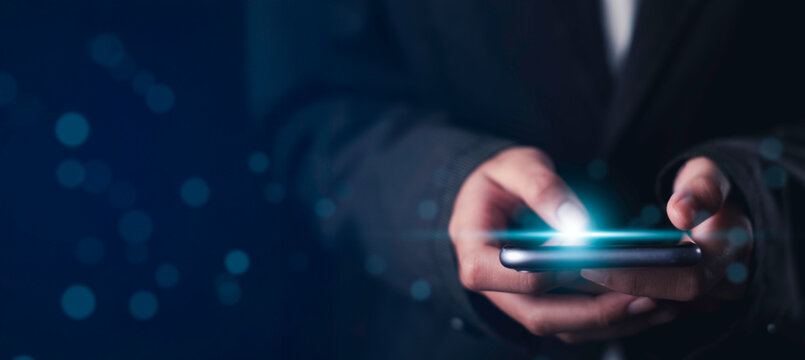 Social application usage concept showing businessman using smartphone with glowing screen effect. Represents scrolling, tapping, and digital interaction with mobile app interface in real-time. - Powered by Adobe