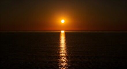 Obraz premium Golden orange sun setting over a calm ocean horizon, with a beautiful shimmering reflection on the water, creating a serene and peaceful natural landscape
