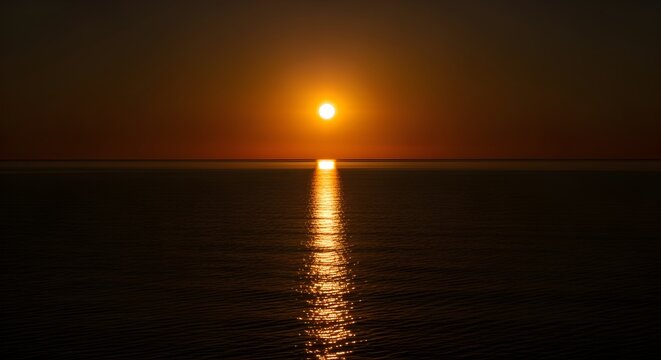 Golden orange sun setting over a calm ocean horizon, with a beautiful shimmering reflection on the water, creating a serene and peaceful natural landscape