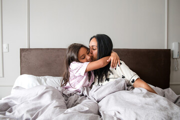 A woman and a child are hugging each other on a bed