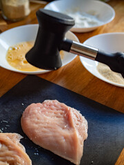 Cooking breaded chicken cutlets- pounding chicken breast, close-up