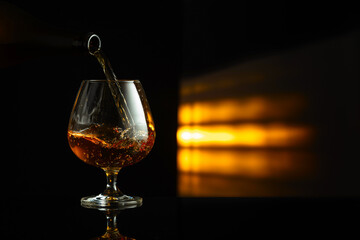 Pouring brandy from a bottle into a snifter.