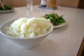 湯気の立つご飯と奥にぼかした中華料理