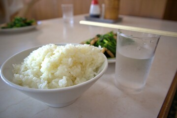 湯気の立つご飯と奥にぼかした中華料理