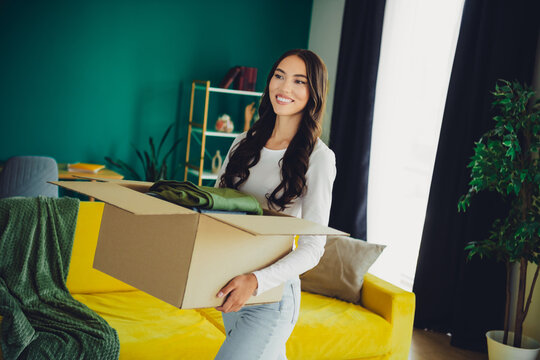 Moving day joy as a young woman packs a box in a bright home living room smiling and ready to start
