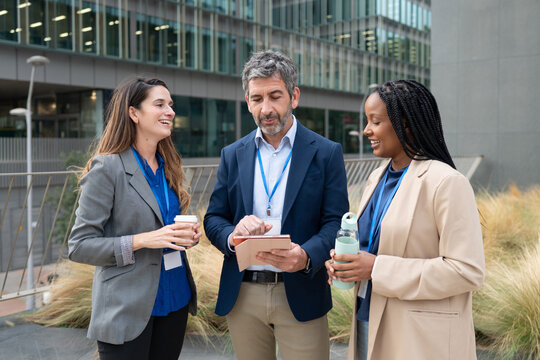 Diverse business team collaborating outdoors with digital tablet