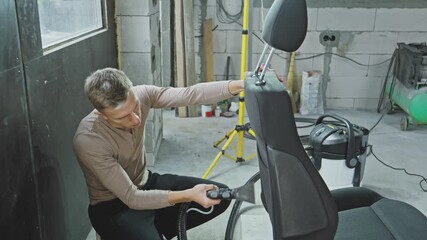 Detailed process of cleaning car seat in garage using washing vacuum cleaner. Watch as seat is vacuumed and washed carefully to ensure it looks great and stays fresh. 4K, UHD
