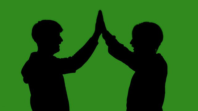 Black silhouettes of two men greet each other with a high five against a green chroma key background. Minimalist contrast and modern visual composition, mockup.