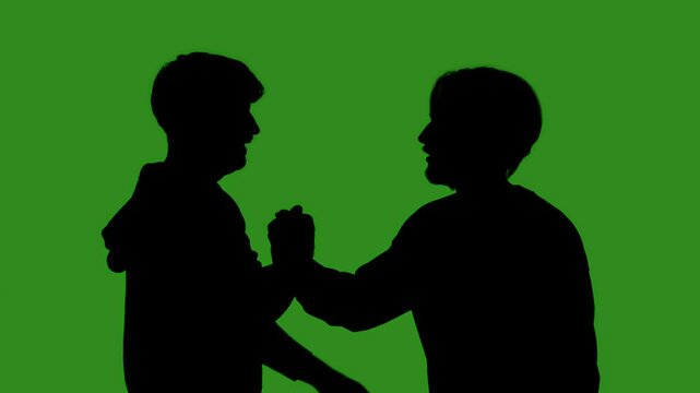 Black silhouettes of two men greet each other with a high five against a green chroma key background. Minimalist contrast and modern visual composition, mockup.