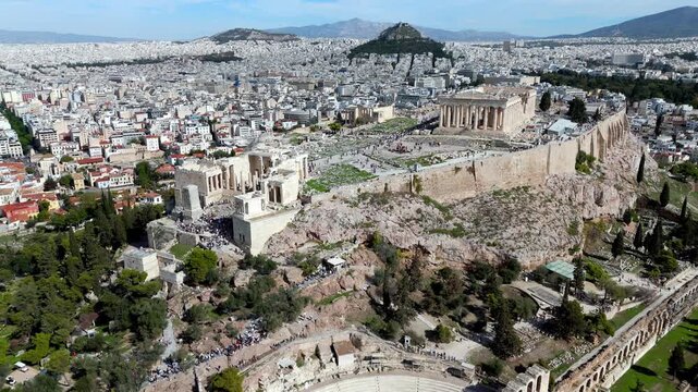 Flying high and approaching from above the Acropolis summit: Parthenon, Propylaea, Erechtheion, and Athena Nike temple with tourists exploring the ruins.