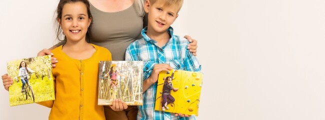 Little girl and boy holding framed family photo indoors, closeup