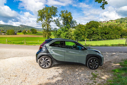 LASSY, FRANCE - SEPTEMBER 26, 2025: Green Toyota Aygo X Edge car driving on an French country road.