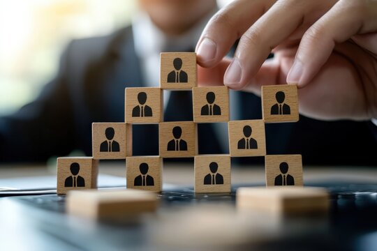 Building the Corporate Ladder: A business executive meticulously constructs a pyramid of wooden blocks, each bearing the imprint of a professional silhouette. The act symbolizes building, strategy.