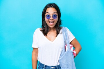 Young caucasian woman holding a beach bag isolated on blue background with surprise facial expression