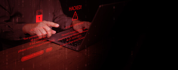 Hands using laptop with hacking alert and access denied message on screen, representing password breach, account compromise, identity theft, cybersecurity threat, data stealing, and online fraud.
