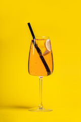 Glass of citrus cocktail with straw on yellow background