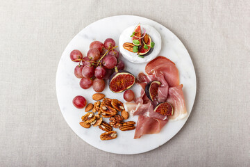 Appetizer board with meat, cheese, grapes, nuts and fresh figs.