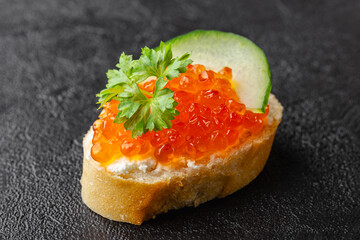Baguette appetizer with red caviar, cucumber and parsley