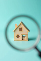 a miniature house under magnifying glass on blue background